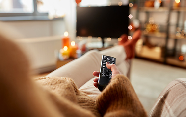 Image showing young woman watching tv at home on halloween