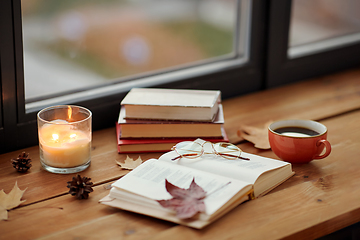 Image showing book, coffee and candle on window sill in autumn