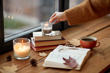 Image showing hand with match lighting candle on window sill