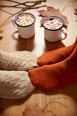 Image showing couple of feet in socks, coffee and autumn leaves