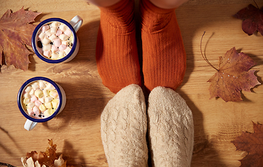 Image showing couple of feet in socks, coffee and autumn leaves