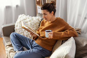 Image showing woman drinking coffee and reading book at home