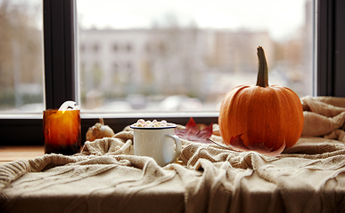 Image showing cup of marshmallow, candle and pumpkin on window