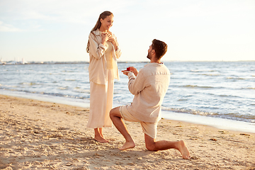 Image showing man with ring making proposal to woman on beach