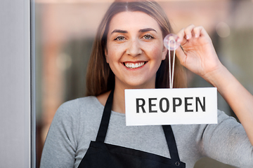 Image showing happy woman hanging reopen banner to door glass