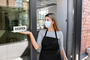 Image showing woman in mask showing reopen banner on door glass