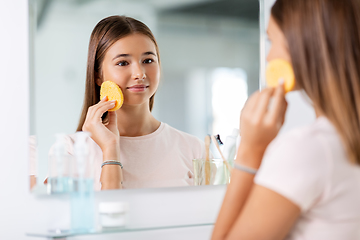 Image showing teenage girl cleaning face with sponge at bathroom