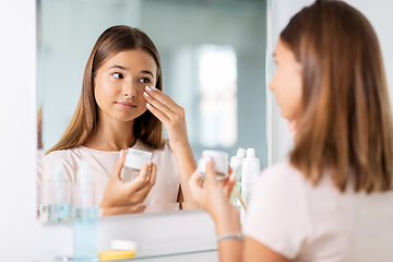 Image showing teenage girl with moisturizer at bathroom