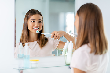 Image showing teen girl with electric toothbrush brushing teeth