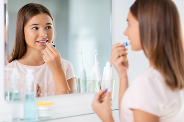 Image showing teenage girl applying lip balm at bathroom