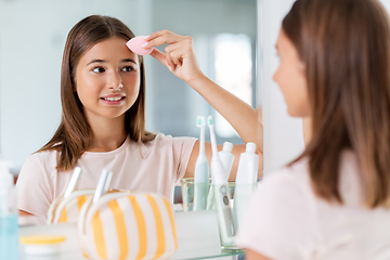 Image showing teenage girl applying foundation to face