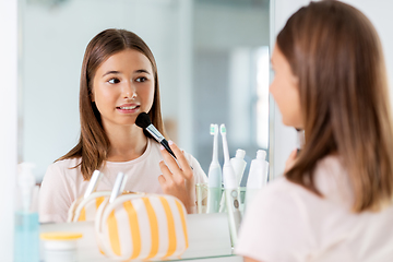 Image showing teenage girl applying powder to face at bathroom