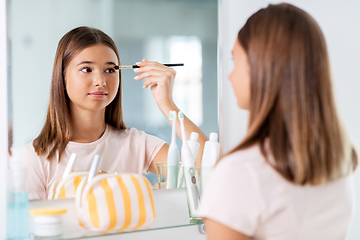 Image showing teenage girl applying eye shadow at bathroom