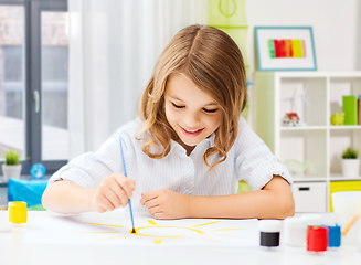 Image showing happy girl with brush and colors drawing at home