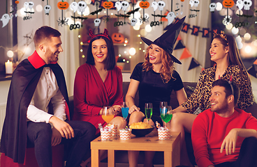 Image showing happy friends in halloween costumes at home party