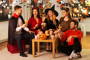 Image showing happy friends in halloween costumes at home party