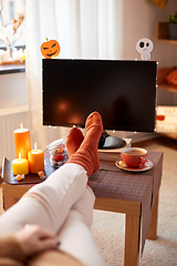 Image showing young woman watching tv at home on halloween