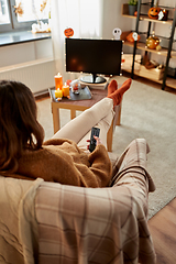 Image showing young woman watching tv at home on halloween