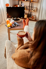 Image showing woman watches tv and drinks cocoa on halloween