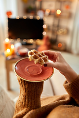 Image showing hands of young woman eating waffle at home