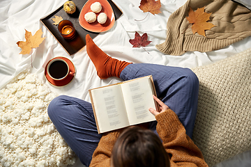 Image showing young woman reading book at home in autumn