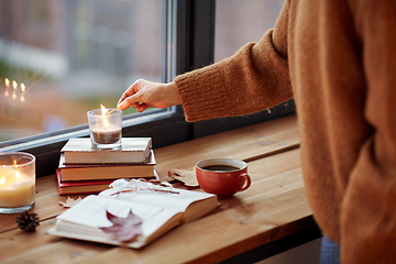 Image showing hand with match lighting candle on window sill