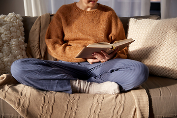 Image showing woman in warm sweater reading book at home