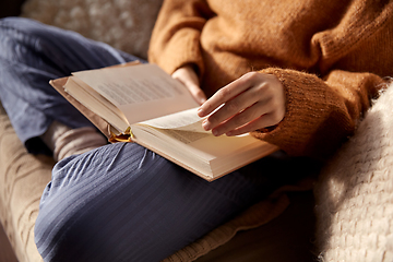 Image showing woman in warm sweater reading book at home