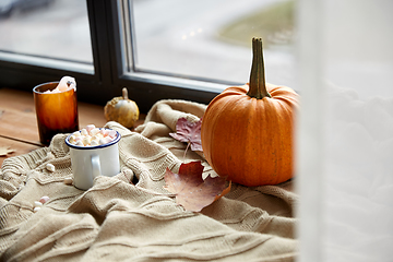 Image showing cup of marshmallow, candle and pumpkin on window