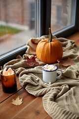 Image showing cup of marshmallow, candle and pumpkin on window