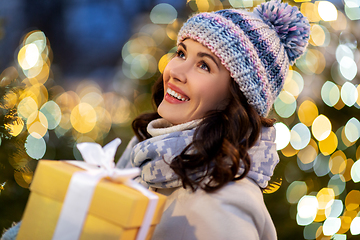 Image showing happy woman with christmas gift over lights