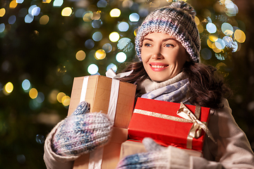 Image showing happy woman with christmas gifts over lights