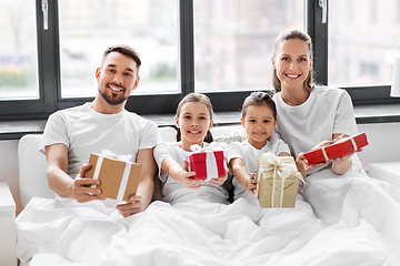 Image showing happy family with christmas gifts in bed at home