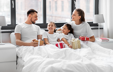 Image showing happy family with christmas gifts in bed at home