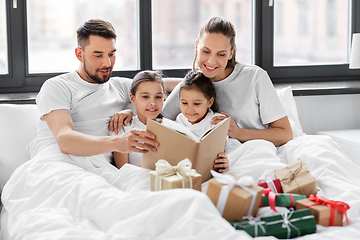 Image showing happy family reading book in bed on christmas