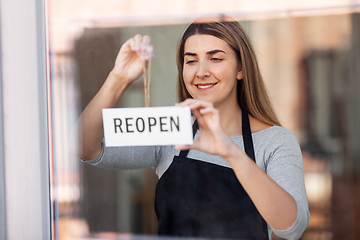 Image showing happy woman hanging reopen banner to door glass