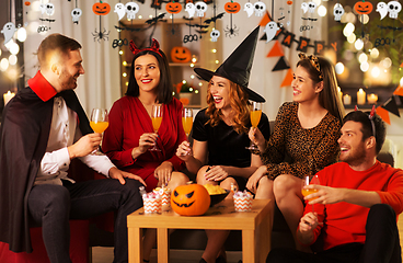 Image showing happy friends in halloween costumes at home party