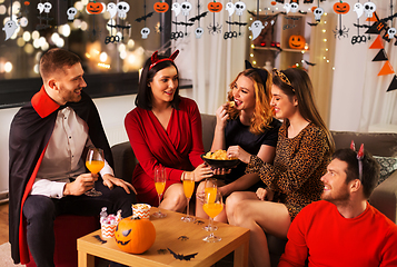 Image showing happy friends in halloween costumes at home party