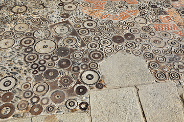 Image showing Unusual floor with pattern from pebbles, brick and rusty metal d