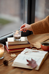 Image showing hand with match lighting candle on window sill