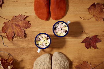 Image showing couple of feet in socks, coffee and autumn leaves