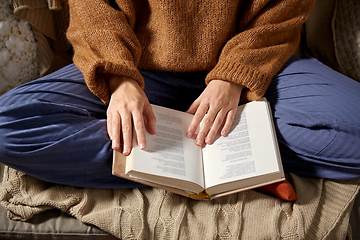 Image showing woman in warm sweater reading book at home