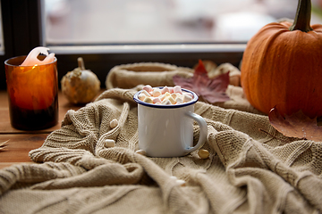 Image showing cup of marshmallow, candle and pumpkin on window