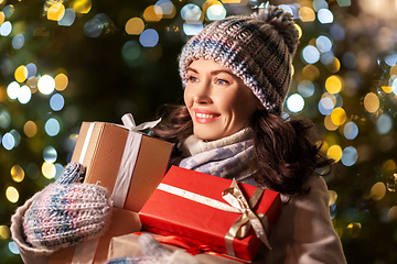 Image showing happy woman with christmas gifts over lights