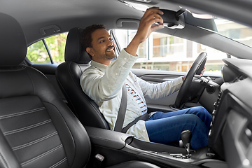 Image showing happy indian man or driver adjusting mirror in car