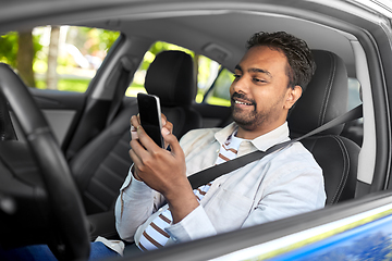 Image showing smiling indian man in car using smartphone