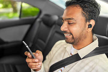 Image showing passenger with earphones and cellphone in taxi car