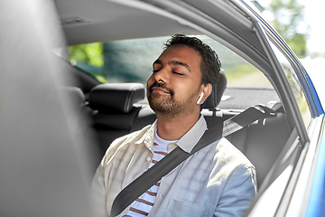 Image showing indian male passenger with earphones in taxi car