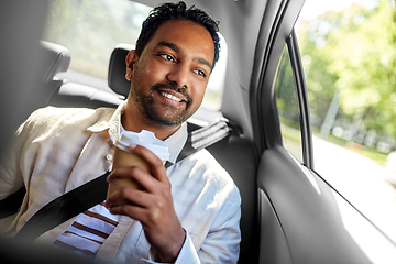 Image showing indian man with takeaway coffee on car back seat