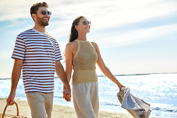 Image showing happy couple with picnic basket walking on beach